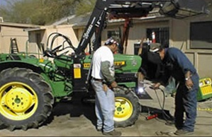 Two people servicing a tractor outside of a house