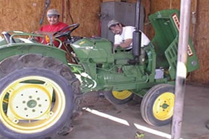 Two people servicing a tractor inside a garage 